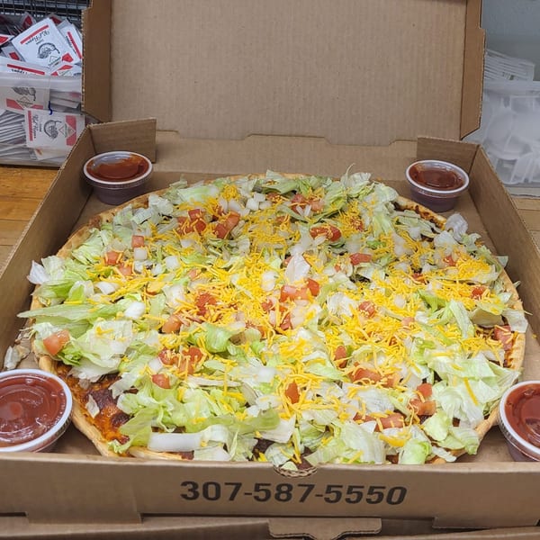 Tossers Pizza & Beer's taco pizza, topped with lettuce, tomatoes, onions, and shredded cheese in a box.