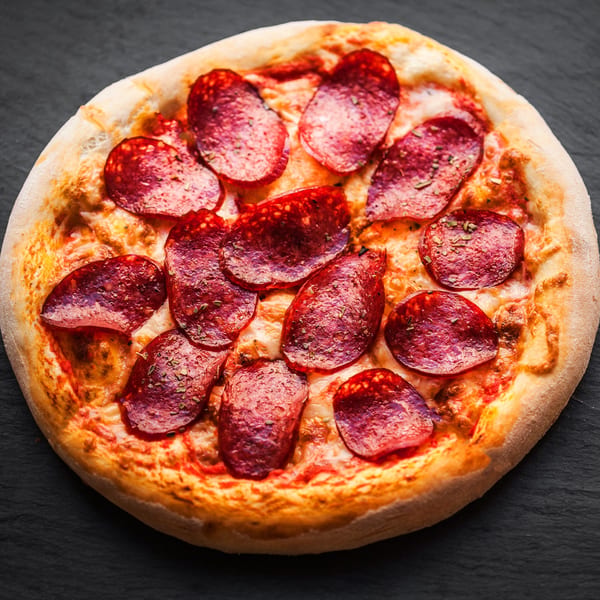 A close-up of a Tossers Pizza & Beer pepperoni pizza with a golden crust on a dark surface.