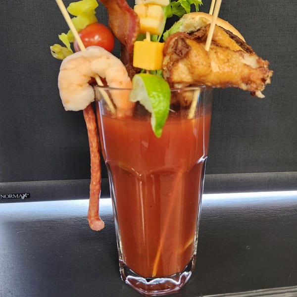 A Bloody Mary cocktail from Tossers Pizza & Beer, garnished with shrimp, bacon, cheese, and a chicken wing.